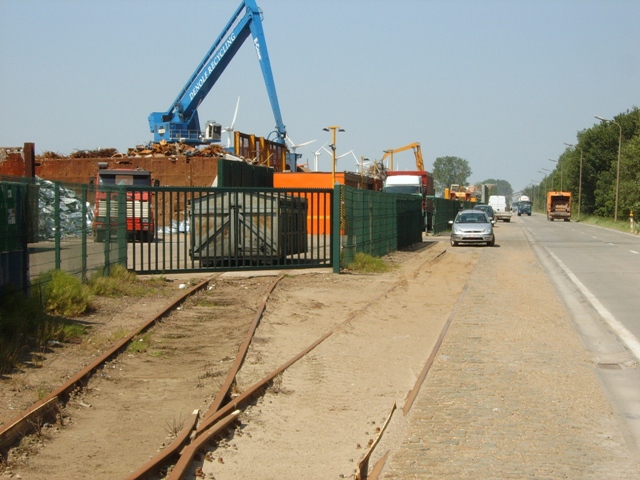 Hier kwamen de treinen aan bij de aansluiting van Denolf Recycling. Links het spoor dat zich binnen de aansluiting begeeft richting weegbrug en laadspoor, rechts een spoor met koetzak die gebruikt werd voor rangeringen en het stallen van materieel.